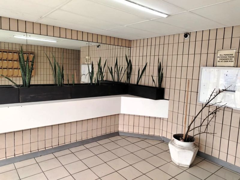 Apartment building entrance lobby featuring tiled walls and flooring, built-in mirror, and integrated mailboxes.