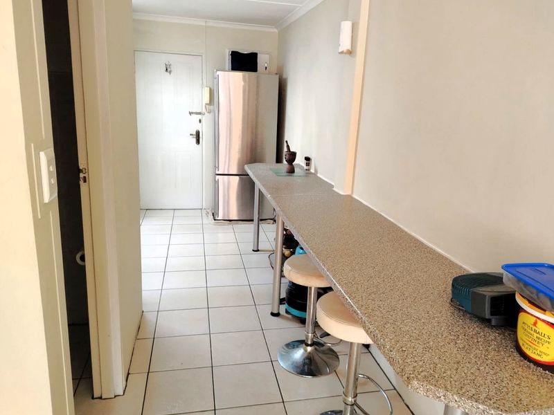 A functional kitchen area featuring a long breakfast bar, tiled flooring, and an integrated intercom system near the entrance.