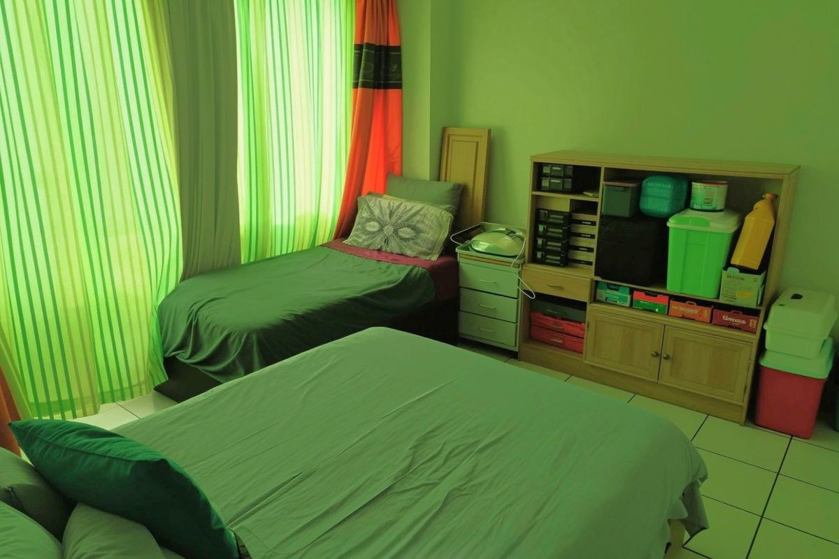 A bedroom featuring tiled flooring and large windows with curtains, providing natural light to the space.