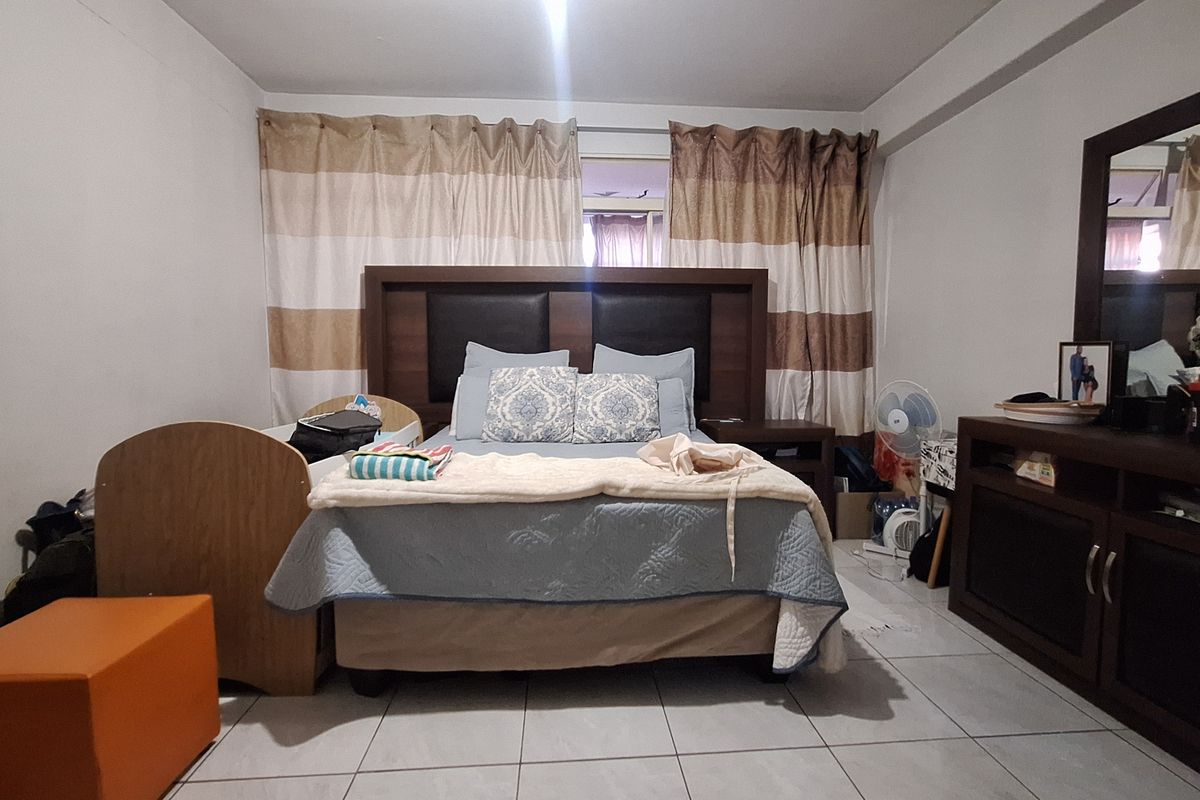 A standard bedroom featuring tiled flooring and neutral wall finishes, providing a functional space for rest.