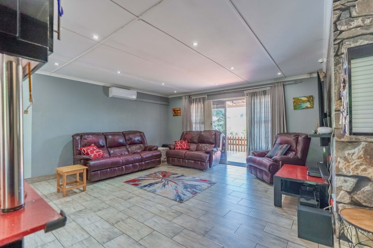 Spacious living room featuring tiled flooring, a stone accent wall, split-system air conditioning, and direct access to an outdoor patio area.
