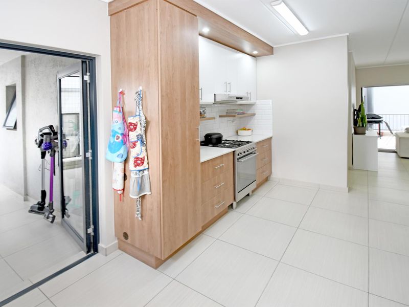 Modern kitchen featuring light wood and white cabinetry, stone countertops, subway tile backsplash, and a gas stove with an integrated extractor fan.