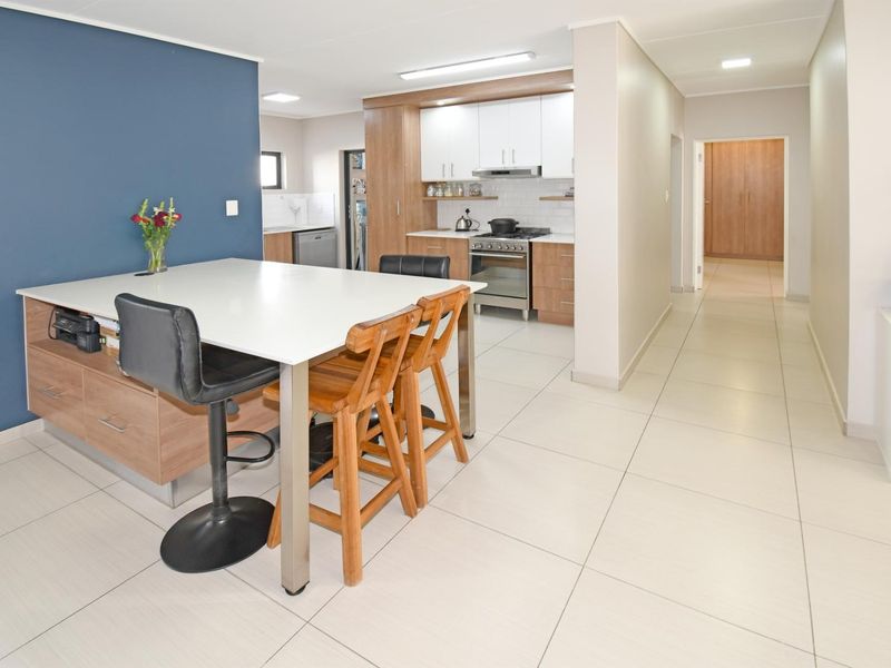 Modern open-plan kitchen and living area featuring a central island, tiled flooring, and contemporary cabinetry with integrated appliances.