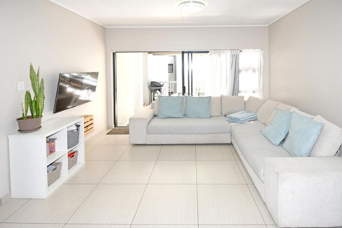 A bright and spacious living room featuring neutral tiled flooring and a large sliding glass door providing access to the outdoor patio area.