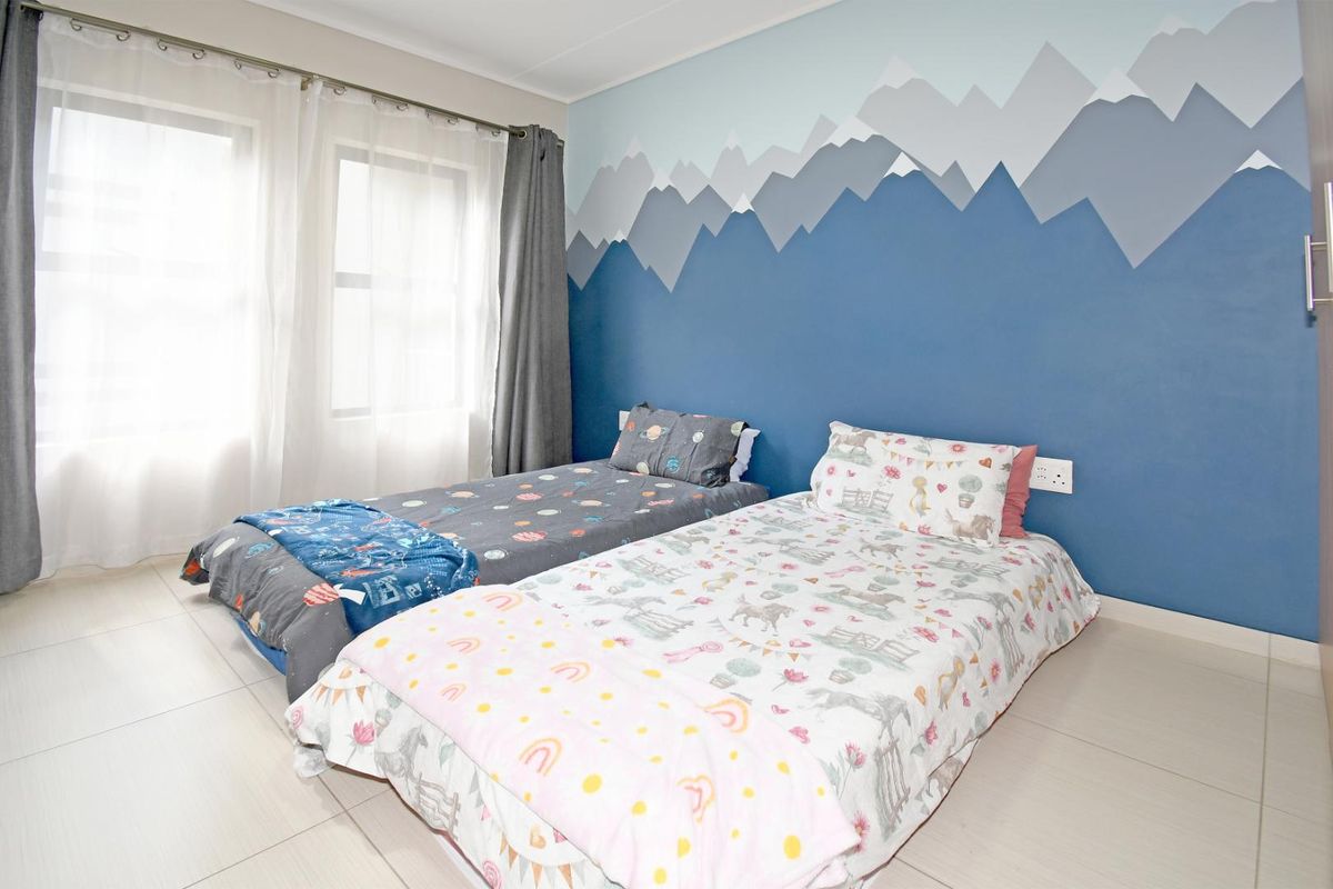 A bright bedroom featuring tiled flooring, a built-in wardrobe, and a decorative mountain-themed accent wall.