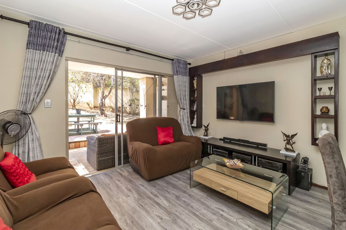 A comfortable living room featuring wood-look laminate flooring, built-in shelving, and sliding glass doors that open onto a private patio area.