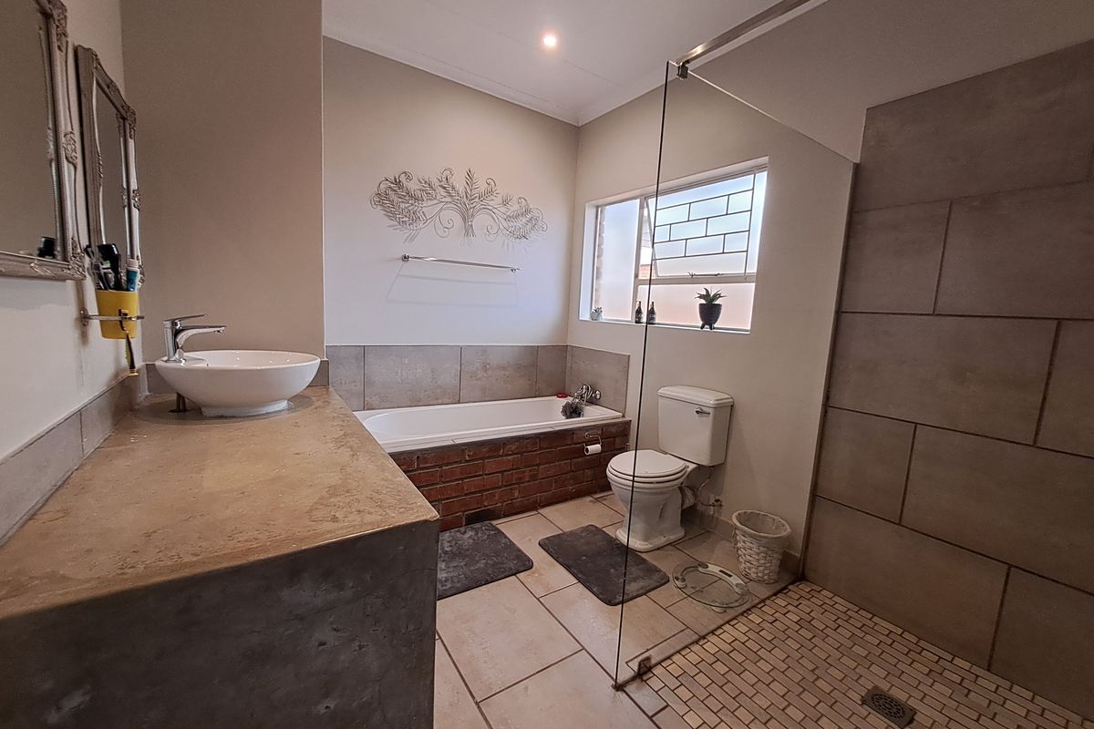 A bathroom featuring a concrete vanity with a vessel sink, a brick-surround bathtub, a toilet, and a walk-in shower with a glass screen.