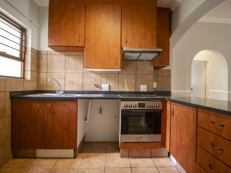 A functional kitchen featuring wooden cabinetry, granite countertops, a built-in oven, and tiled finishes, offering a practical layout ready for modernization.