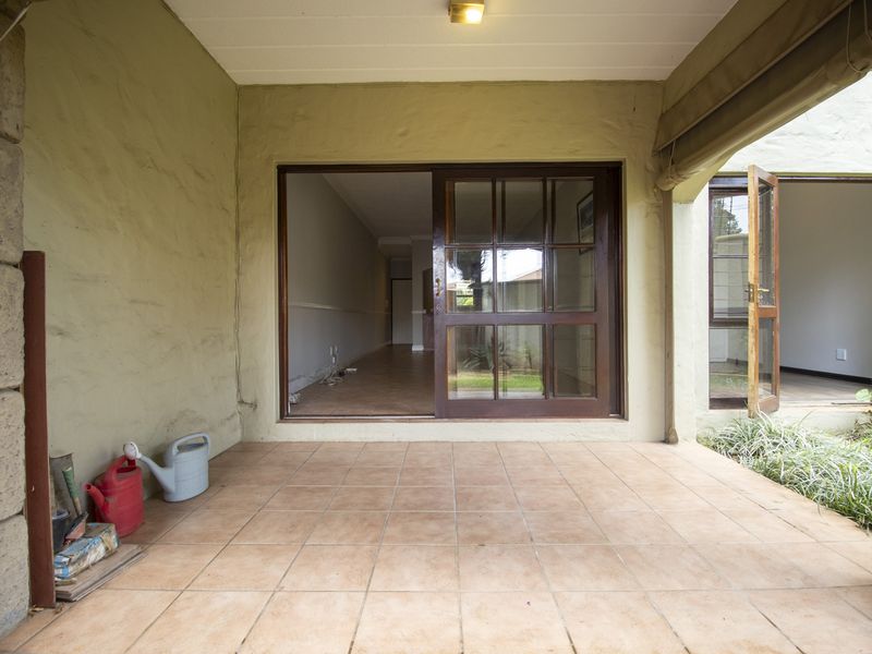 A covered patio area featuring tiled flooring and a sliding glass door providing access to the interior living space.