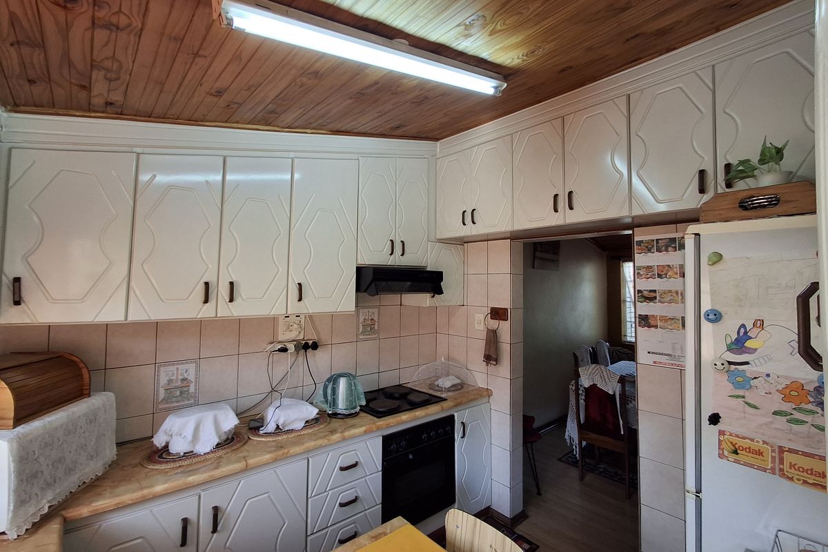 A functional kitchen featuring white cabinetry, a wood-paneled ceiling, tiled backsplash, and built-in oven with extractor fan.