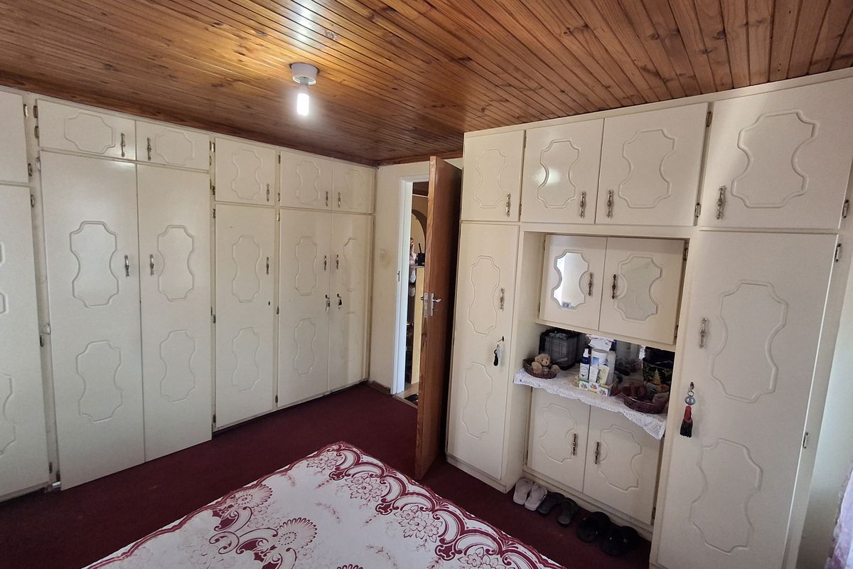 Bedroom featuring extensive built-in cabinetry with integrated vanity and storage, complemented by a timber-clad ceiling.