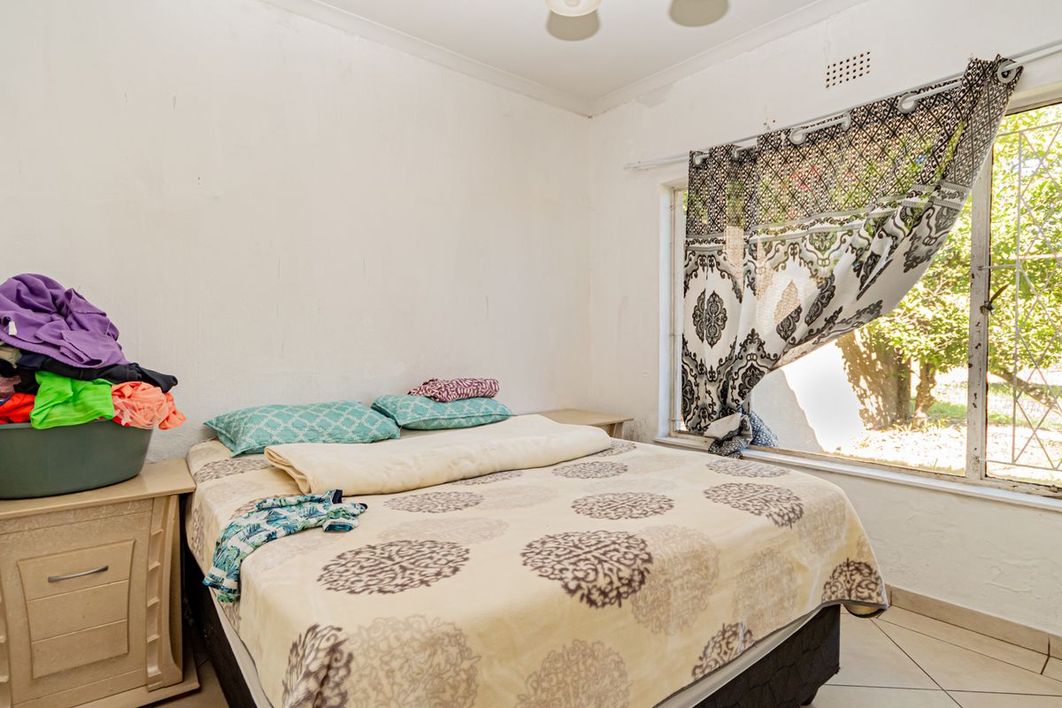 A bedroom featuring tiled flooring, a large window with security bars, and built-in ceiling lighting.