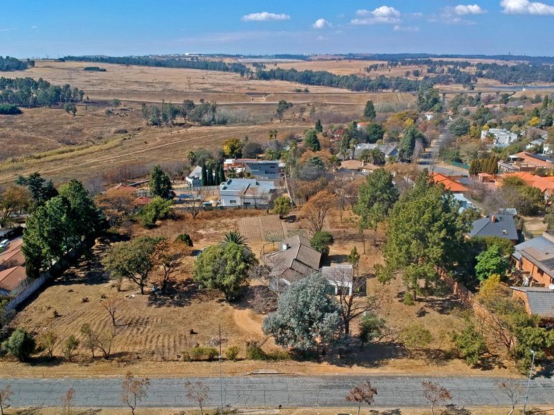 Aerial view of a large residential plot featuring established trees, open land, and surrounding neighborhood infrastructure.