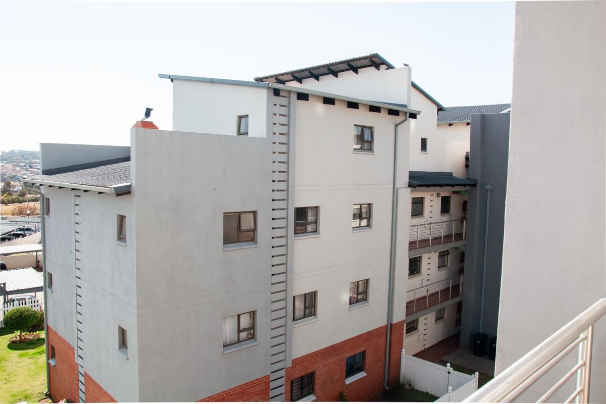 Exterior view of a multi-story apartment building featuring a combination of brick and rendered facade finishes with metal roof detailing.