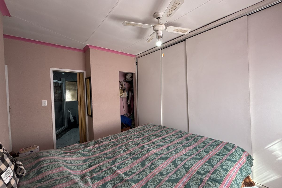A bedroom featuring a ceiling fan, built-in sliding door wardrobes, and direct access to an en-suite bathroom.