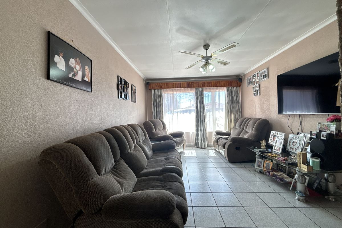 A comfortable living room featuring tiled flooring and a ceiling fan, providing a functional space for relaxation.