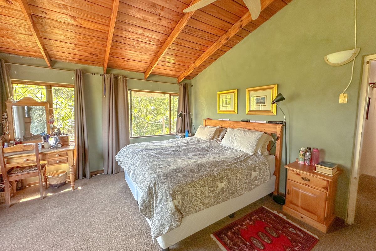 Spacious bedroom featuring a high vaulted timber ceiling, large windows providing natural light, and neutral wall finishes.