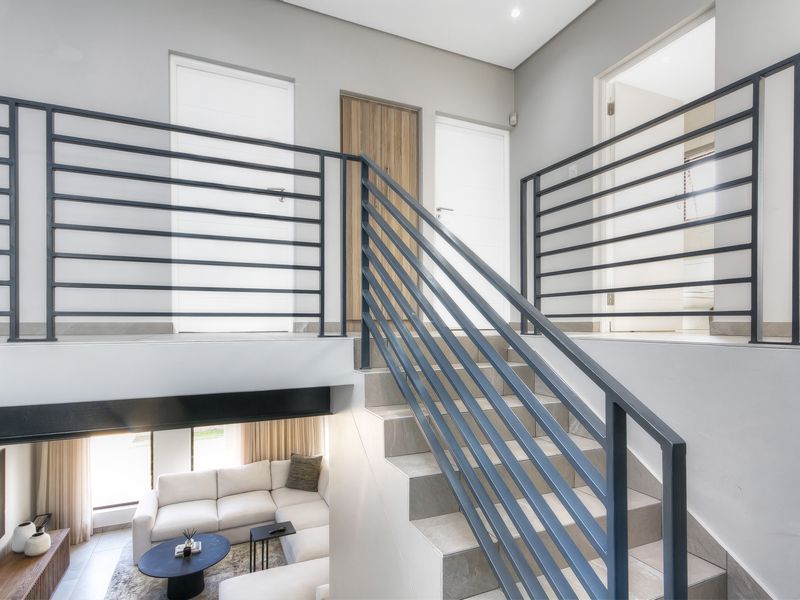 A modern upper-level landing area featuring a tiled staircase with a sleek metal balustrade, providing access to multiple rooms.