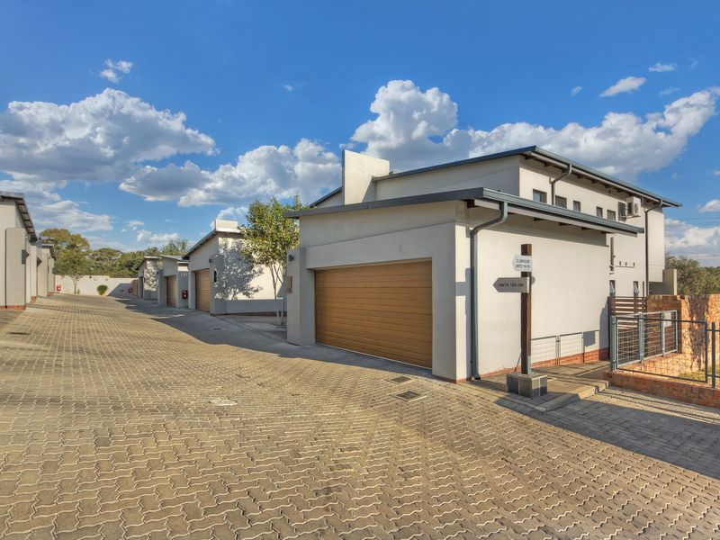 A view of the townhouse complex driveway featuring multiple garage units with paved access and well-maintained exterior facades.