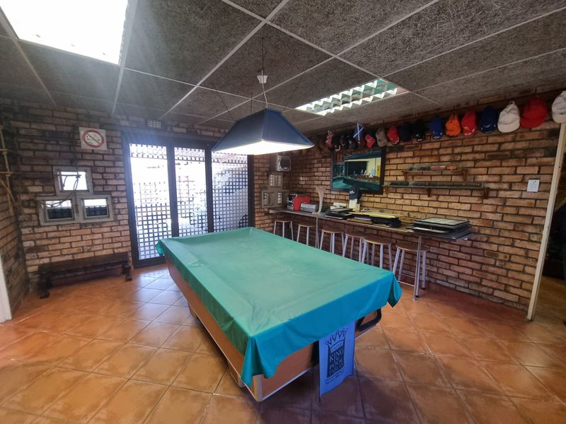 A recreational room featuring exposed brick walls, tiled flooring, acoustic ceiling tiles, and a built-in bar counter with sliding glass door access.