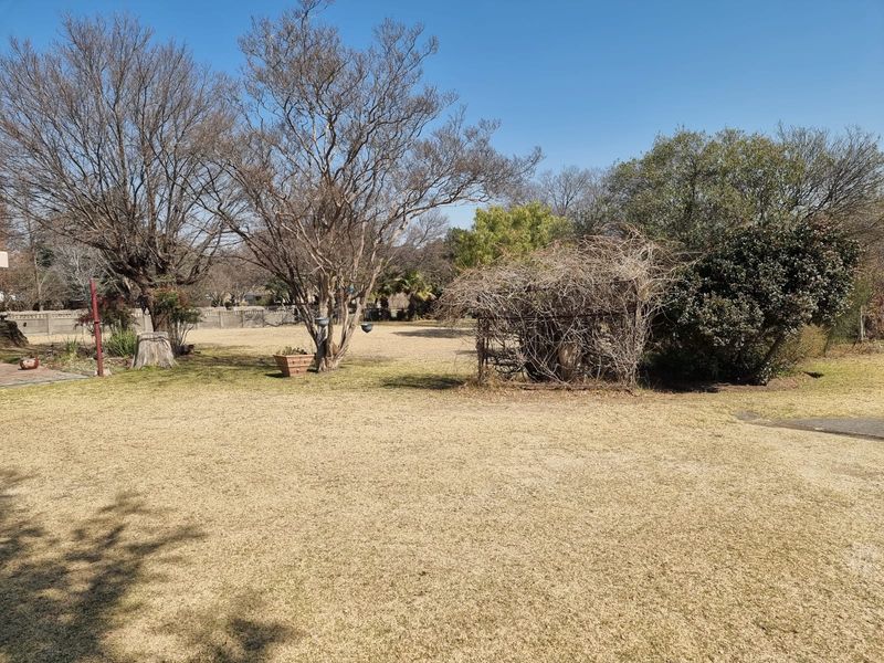 A spacious, open garden area featuring mature trees, established lawn, and perimeter walling, offering significant potential for landscaping and outdoor development.