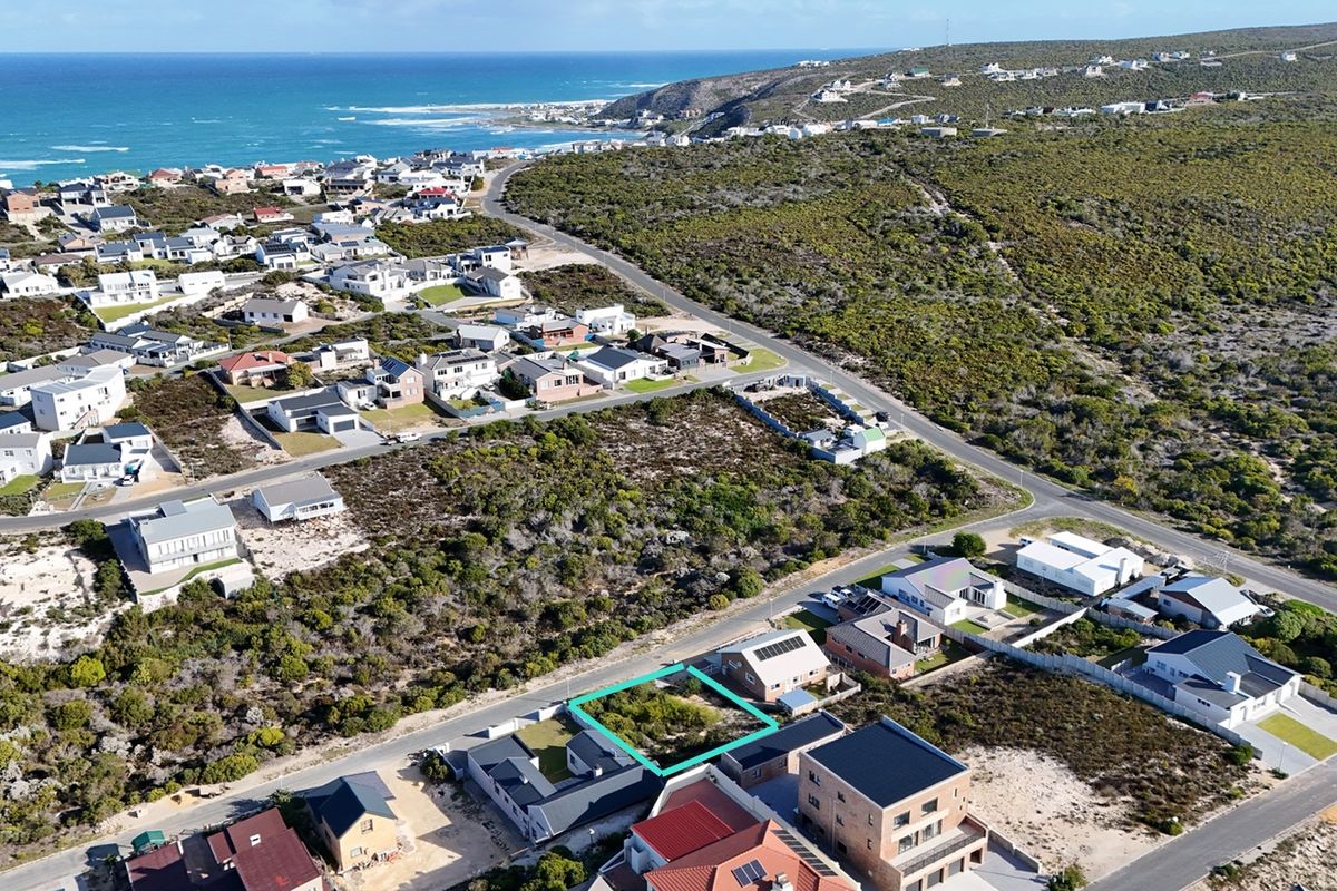 Aerial view of a vacant residential plot situated in a coastal neighborhood, offering potential for development with scenic surroundings.