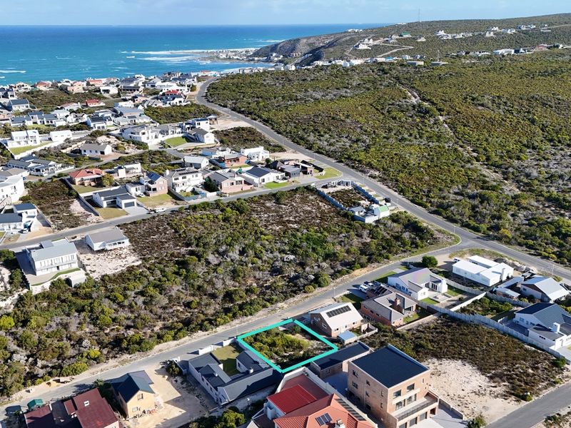Aerial view of a vacant residential plot situated in a coastal neighborhood, offering potential for development with scenic surroundings.