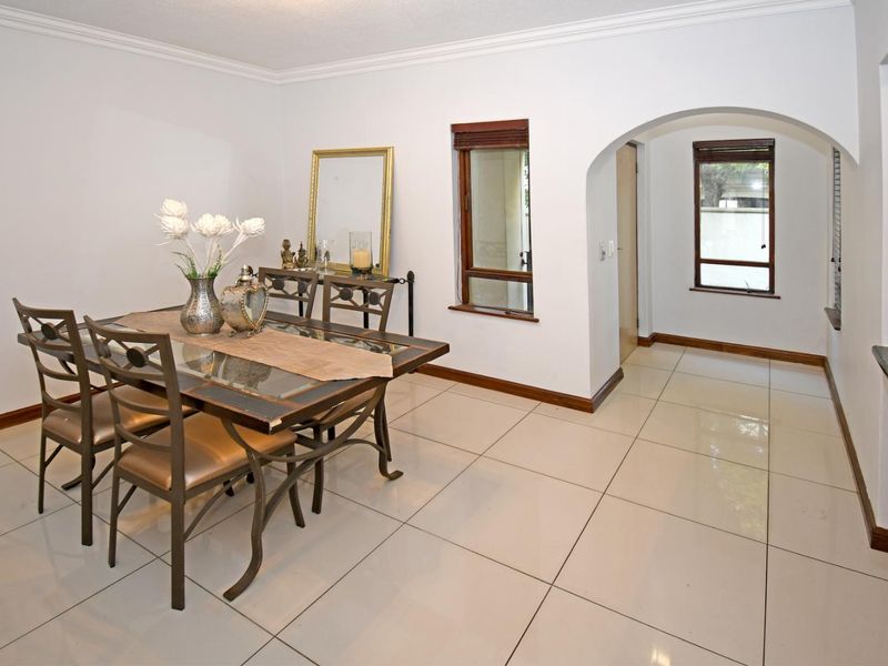 A bright dining room featuring large porcelain floor tiles, an elegant archway leading to an adjacent space, and classic coving details.