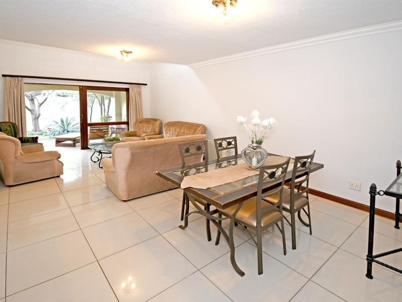 Spacious open-plan living and dining area featuring large format floor tiles and a sliding glass door providing direct access to the outdoor patio.