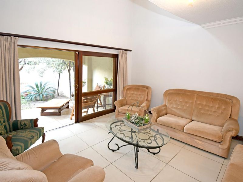 Spacious living room featuring tiled flooring, vaulted ceilings, and large sliding glass doors providing direct access to the outdoor patio area.