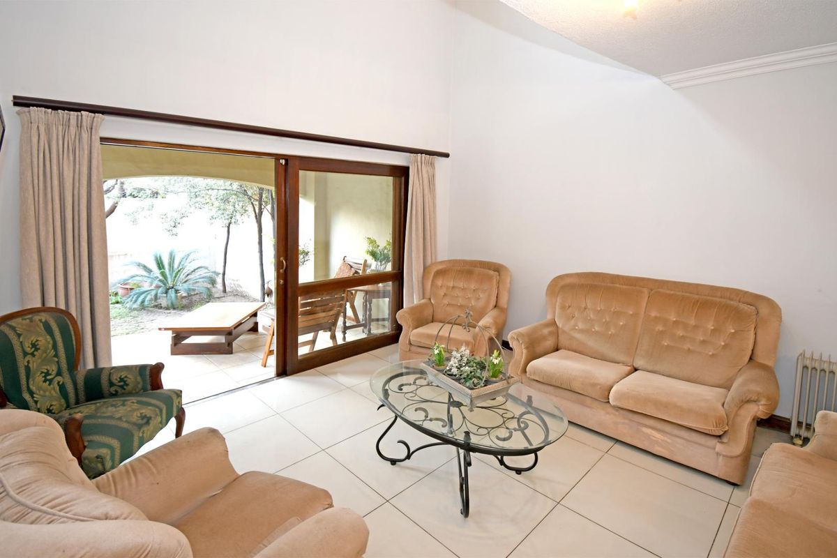 Spacious living room featuring tiled flooring, vaulted ceilings, and large sliding glass doors providing direct access to the outdoor patio area.
