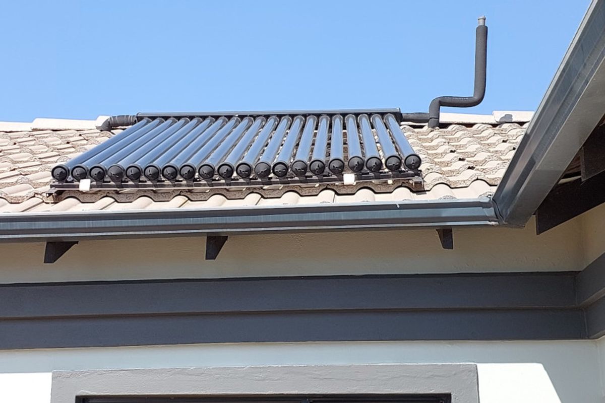 A close-up view of a roof-mounted solar water heating system with evacuated tubes installed on tiled roofing.