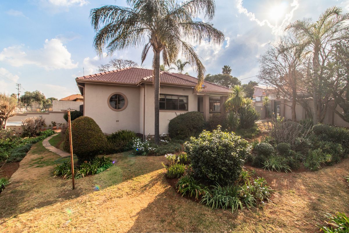 A view of the rear exterior of the house featuring a tiled roof, a distinctive porthole window, and a landscaped garden with a paved walkway.