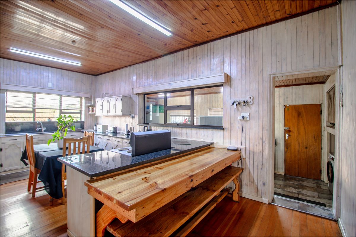 Kitchen featuring timber ceiling and wall paneling, granite island countertop, and integrated breakfast bar, offering a rustic aesthetic with functional layout.