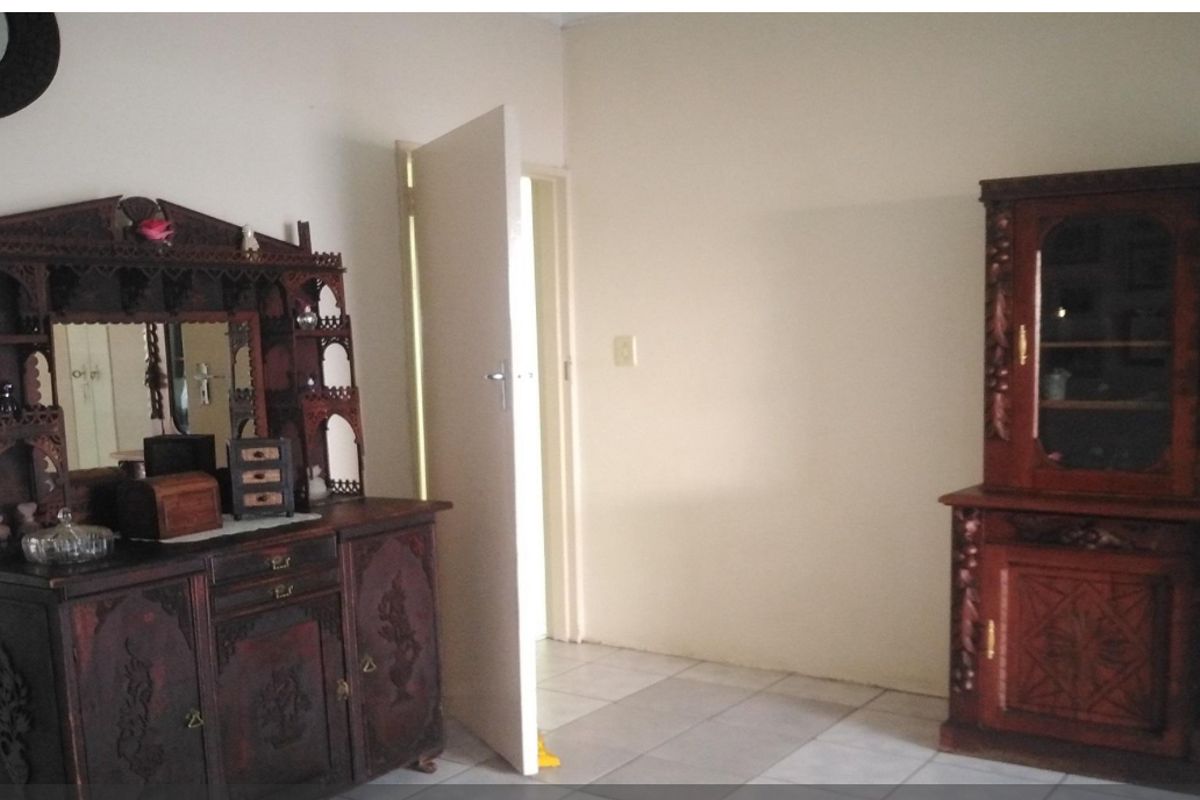 A bedroom featuring tiled flooring and a built-in cupboard, offering a neutral space ready for personalization.