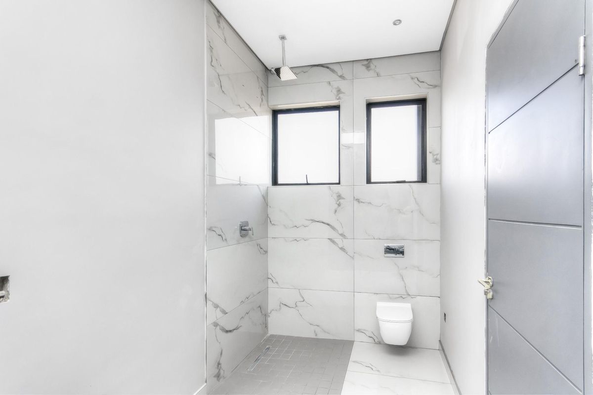 Modern bathroom featuring floor-to-ceiling marble-look wall tiles, a wall-mounted toilet, and a walk-in shower area with a rainfall showerhead.
