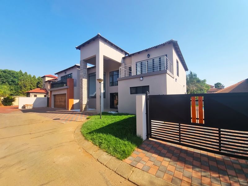 Modern double-story residential home featuring a paved driveway, double garage, and a balcony, set within a secure estate environment.