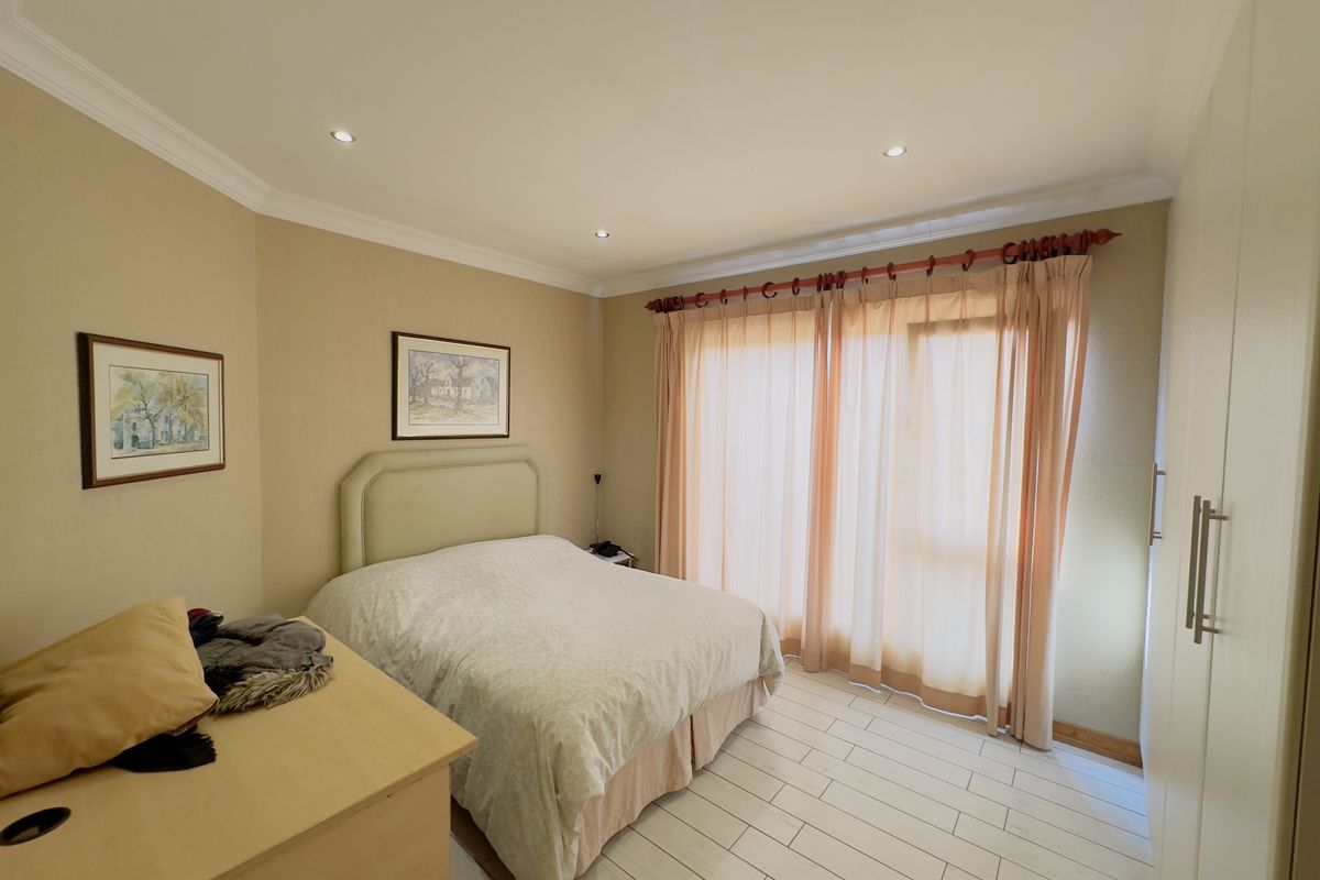 A well-maintained bedroom featuring tiled flooring, recessed ceiling lighting, and built-in cupboards, with direct access to an outdoor area through sliding glass doors.