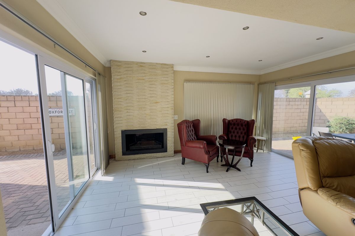 Spacious living room featuring a modern stone-clad fireplace, tiled flooring, and large sliding glass doors providing seamless access to the outdoor patio area.