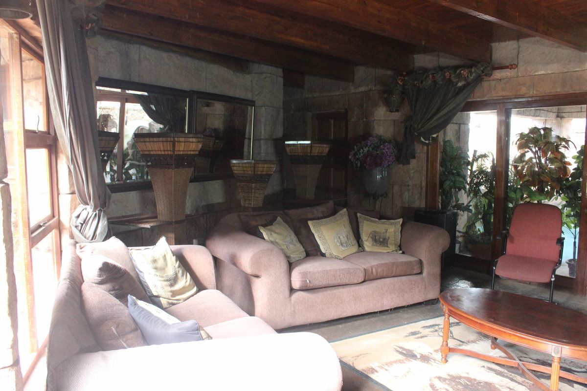 Rustic living room featuring exposed timber ceiling beams, textured stone masonry walls, and large sliding glass doors providing natural light.