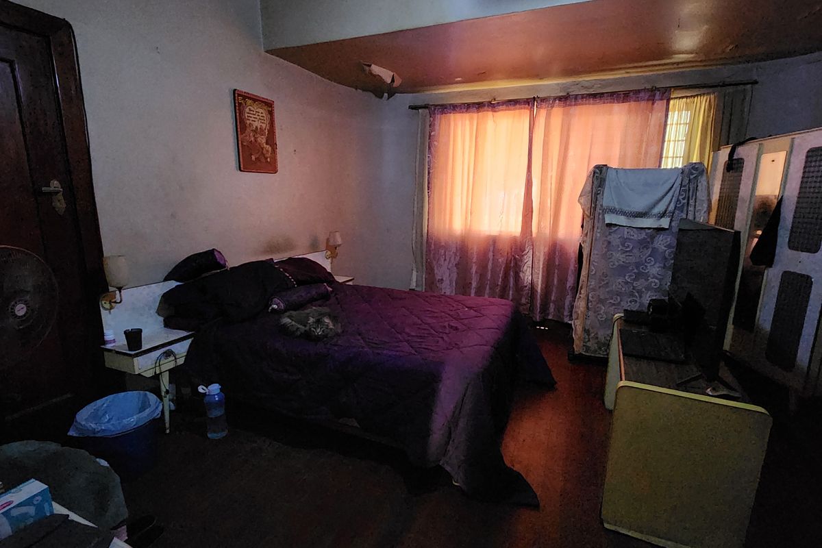 A bedroom featuring hardwood flooring and a built-in wardrobe, currently showing significant signs of wear including ceiling damage and wall staining.