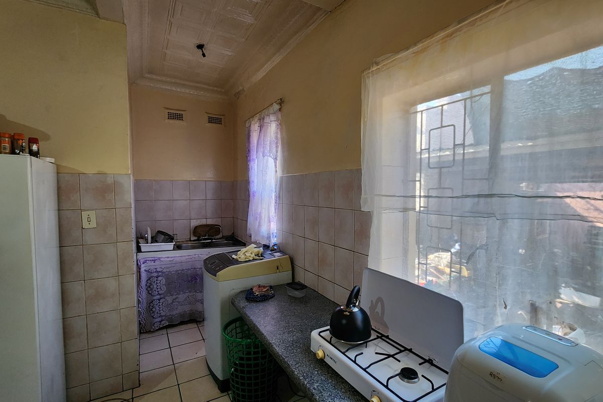 A functional kitchen featuring tiled splashbacks, granite countertops, and security bars on the windows, offering a practical layout for daily use.
