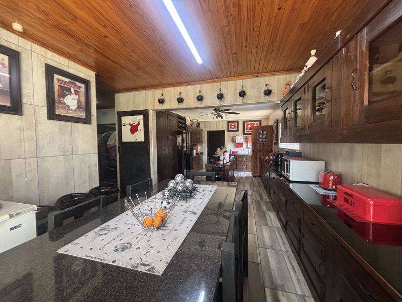 Spacious kitchen featuring extensive dark wood cabinetry, granite countertops, tiled flooring, and a distinctive wooden ceiling with integrated lighting.