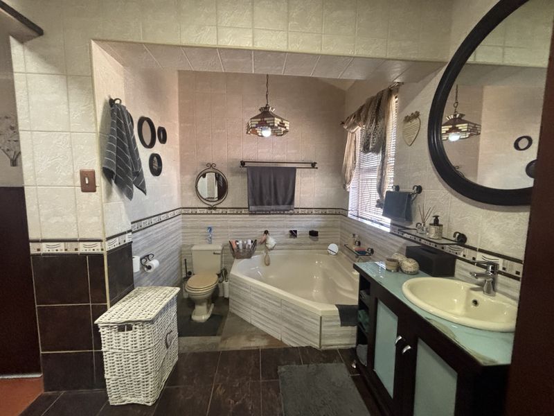 A dated bathroom featuring a corner bathtub, built-in vanity with basin, and tiled finishes throughout.