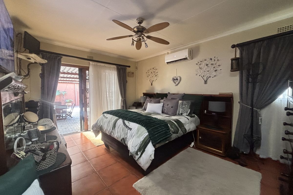 Spacious bedroom featuring tiled flooring, a ceiling fan, split-system air conditioning, and direct access to an outdoor patio area through sliding glass doors.