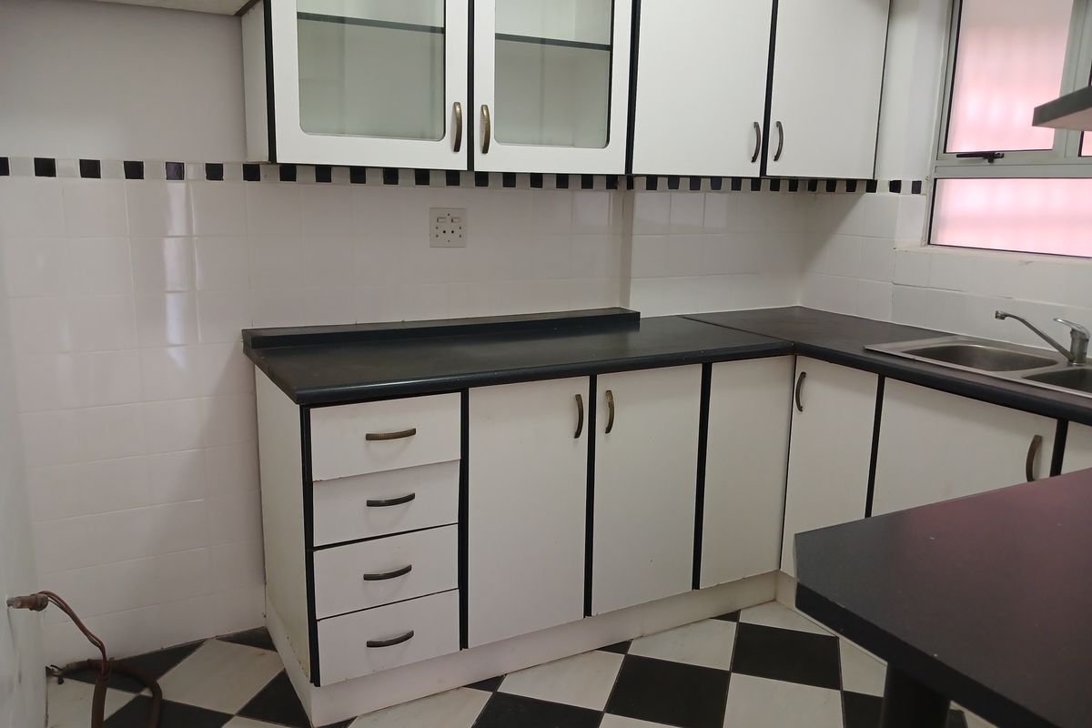 A functional kitchen featuring white cabinetry with black trim, contrasting black countertops, and a classic black-and-white checkered floor.