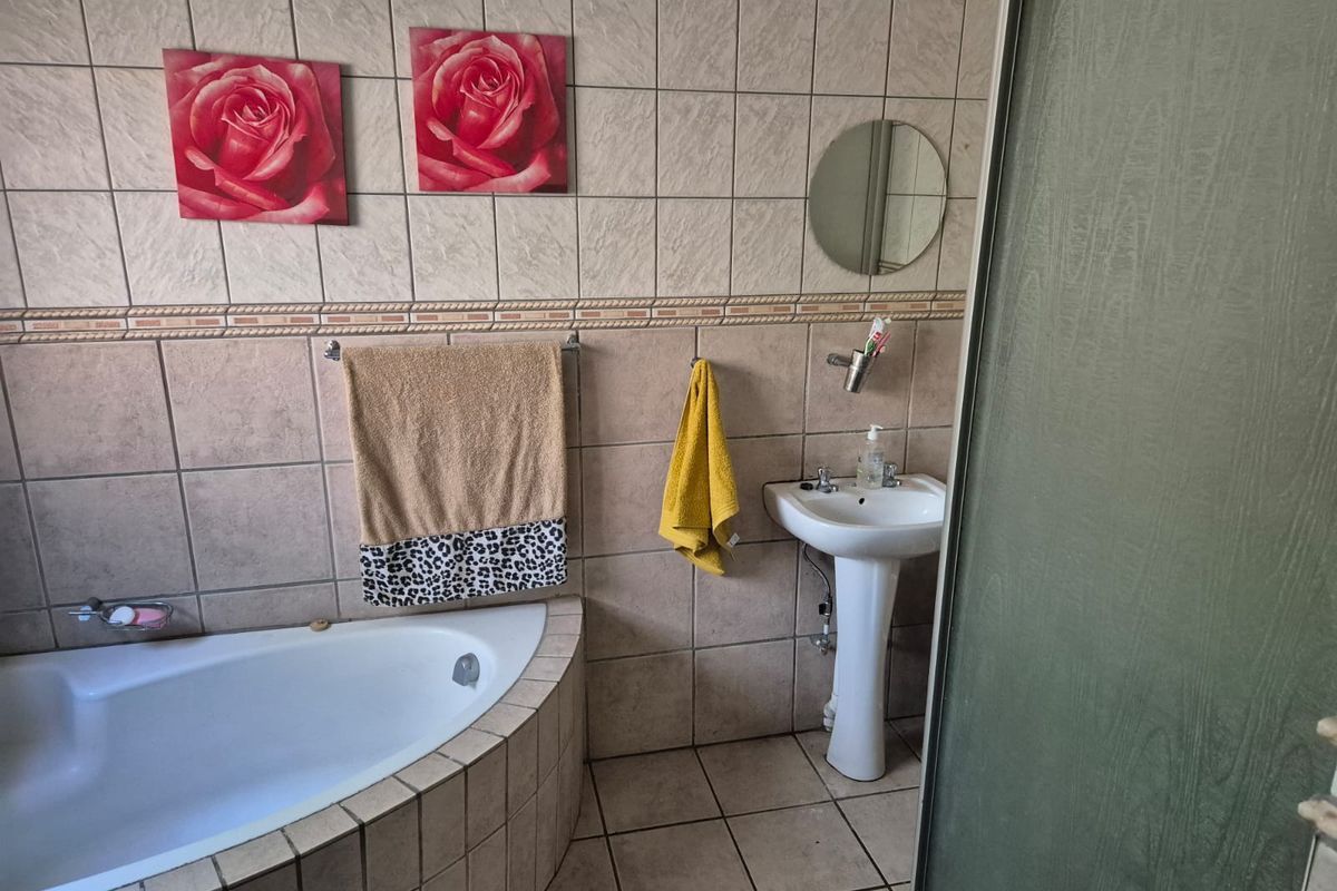 A dated bathroom featuring a corner bathtub, pedestal basin, and shower enclosure with full-height wall tiling.