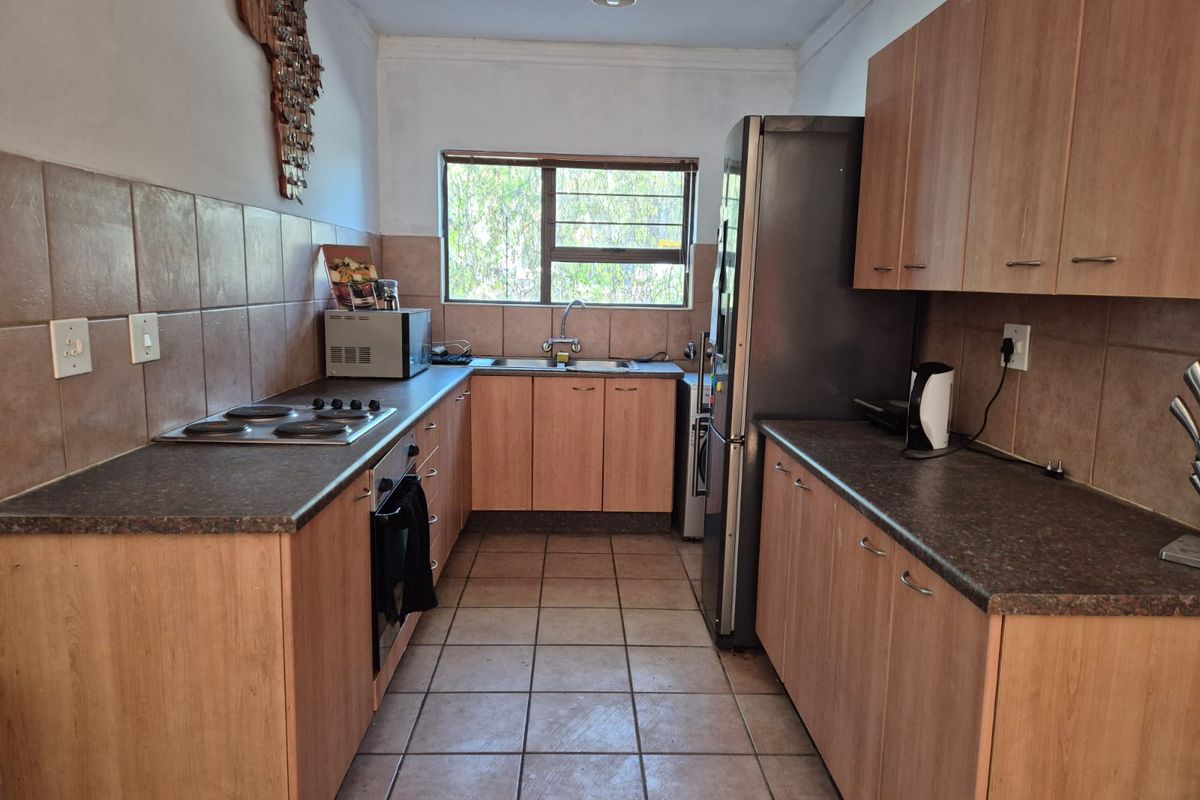Functional kitchen featuring laminate cabinetry, dark countertops, ceramic tile backsplash, and built-in cooking appliances with a window overlooking the exterior.