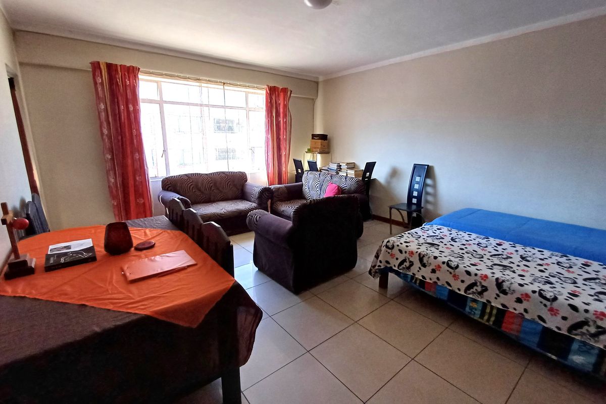 A spacious living area featuring neutral tiled flooring and a large window that provides natural light to the room.