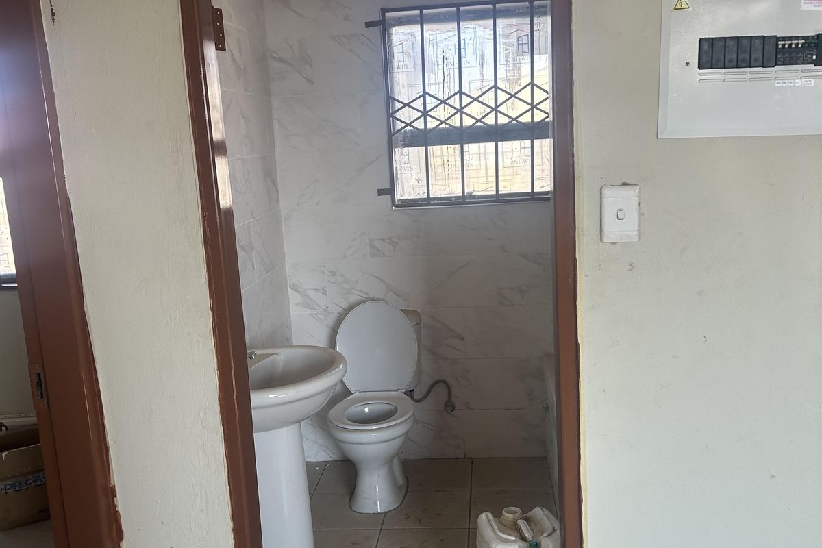 A compact bathroom featuring a pedestal basin, toilet, and tiled finishes, requiring cosmetic updates to improve its overall condition and appeal.